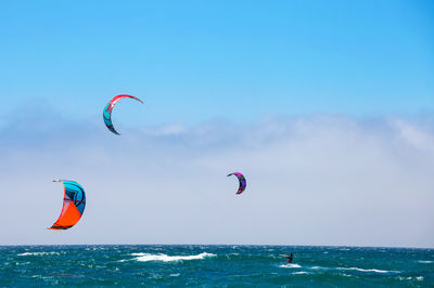 People paragliding in sea against sky