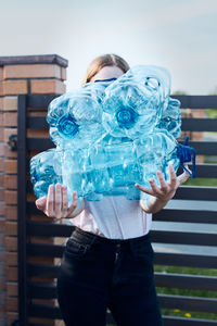 Young woman throwing out empty used plastic water bottles into trash bin