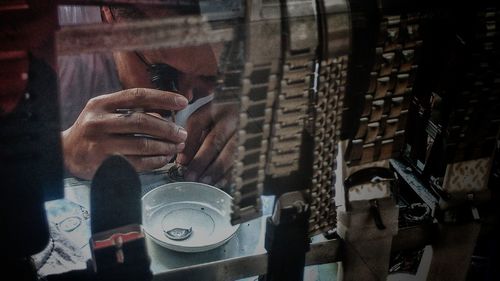 Man repairing wristwatch seen through window