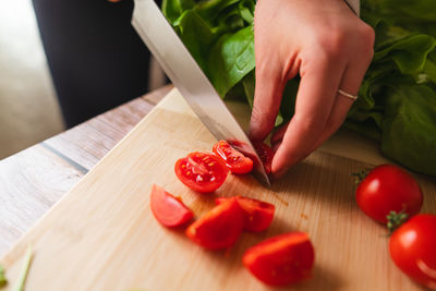 Cropped hand of woman holding bell pepper on cutting board