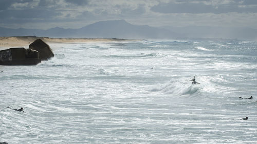 Surfer in sea against sky