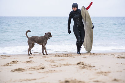 Young woman and her dog going winter surfing in snow