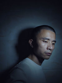 Close-up of sad man looking down against wall in darkroom