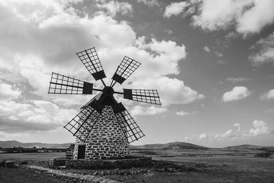 Traditional windmill on field against sky