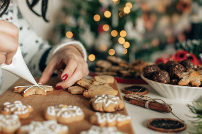 Close-up photo of woman decorating gingerbread christmas cookies at home