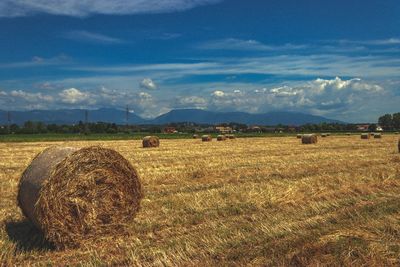 Hay bales on field against sky