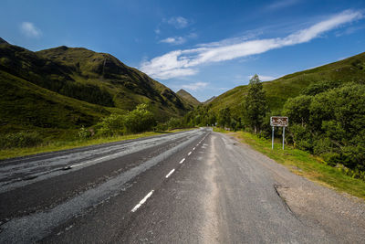 Road by mountains against sky