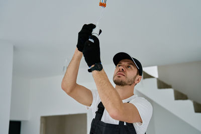 Low angle view of young woman with arms raised standing against wall
