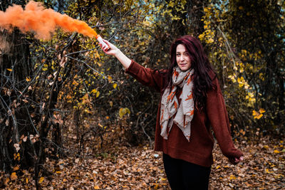 Smiling young woman standing in forest during autumn