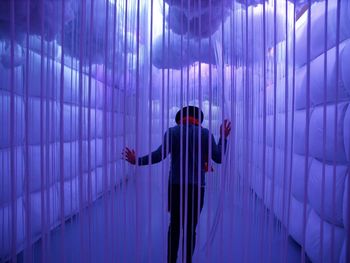 Rear view of man standing against illuminated wall