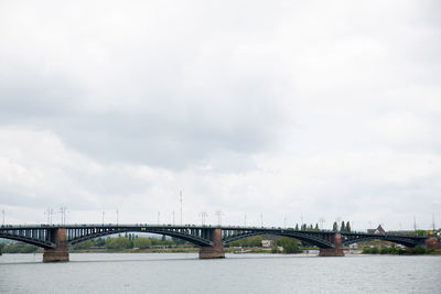 Bridge over river against cloudy sky