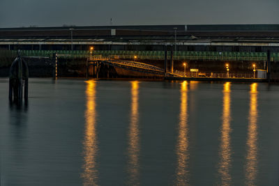 Illuminated bridge over river against sky at night