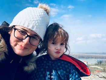 Portrait of happy mother and daughter against sky during winter