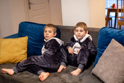 Siblings sitting on sofa at home