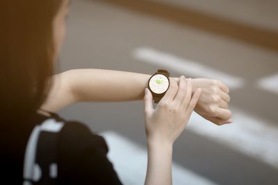 Close-up of woman hand holding clock against blurred background