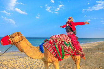 Woman riding camel at beach