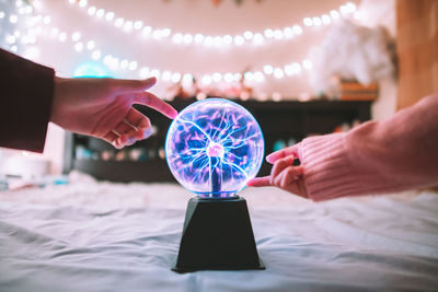 Cropped image of woman hand around plasma ball