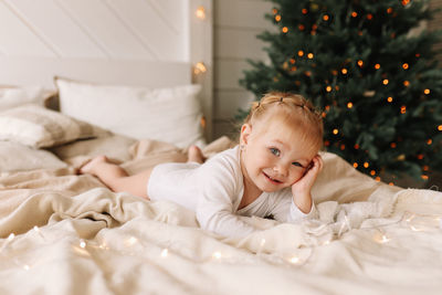 Portrait of happy girl lying on bed at home