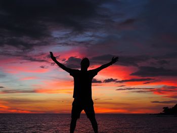 Silhouette woman standing on beach against sky during sunset