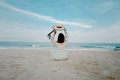 Rear view of woman on beach against sky