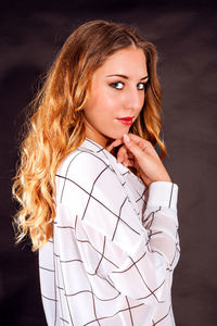 Portrait of young woman standing by wall