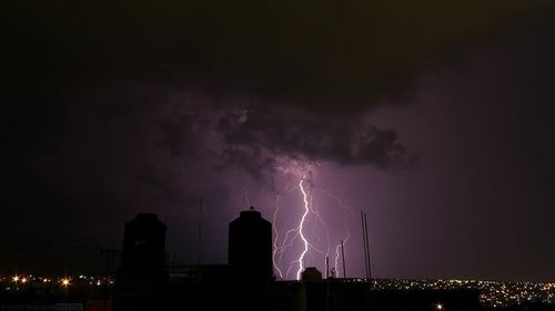 Panoramic view of lightning over city at night