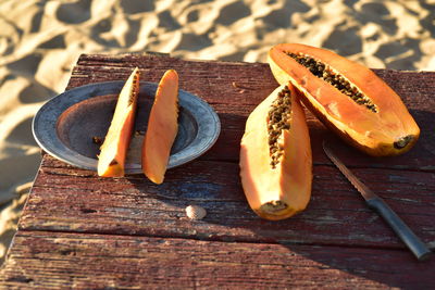 Close-up of fresh papaya slices on rustic wood table on sand beach