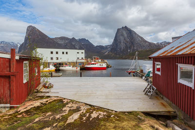 Houses by buildings and mountains against sky