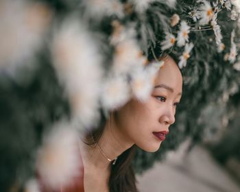 Close-up portrait of young woman amongst flowers