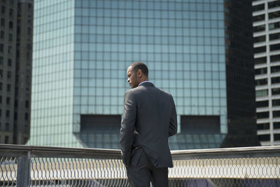 Rear view of businessman standing against office buildings