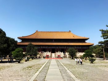 People in front of building against clear sky