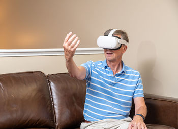 Midsection of man sitting on sofa at home