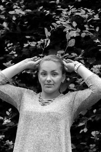 Portrait of young woman standing against tree