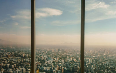 High angle view of buildings against sky seen through glass window