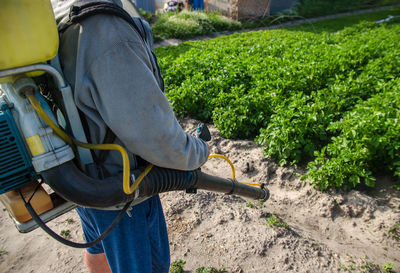 Farmer with a spray machine on potato plantation background. fungicide and pesticide 