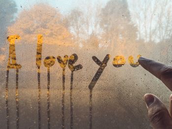 Cropped hand writing i love you text on wet window