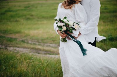 Midsection of couple standing on field