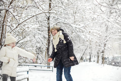 Portrait of smiling couple standing on snow covered field
