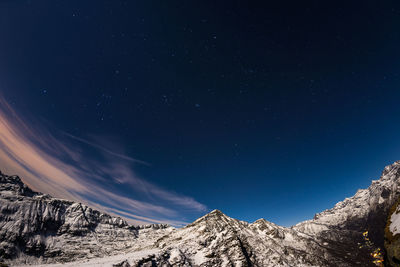 Low angle view of snowcapped mountains against sky at night