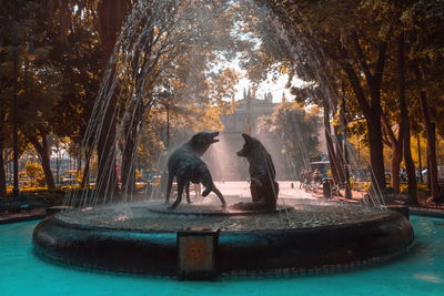 People sitting by statue against trees