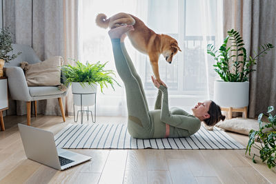 Funny pregnant female doing online yoga with cute shiba inu dog at home. doga yoga or dog training