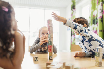 Boy stacking alphabet blocks on table