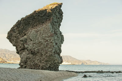 Rock formation on beach against sky