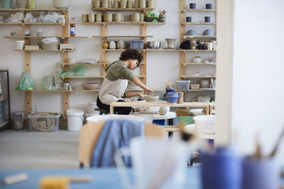 Side view of woman learning pottery in art studio