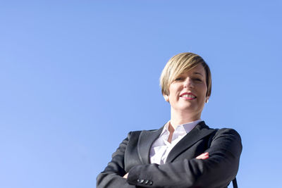 Portrait of businessman standing against clear blue sky