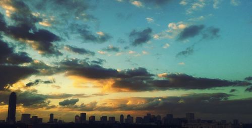 Silhouette cityscape against dramatic sky during sunset