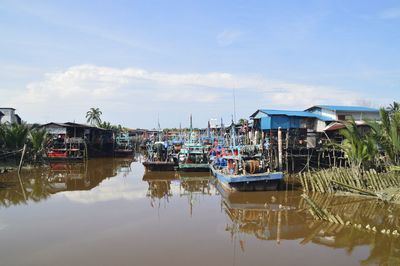 Fishing boats moored at harbor against sky