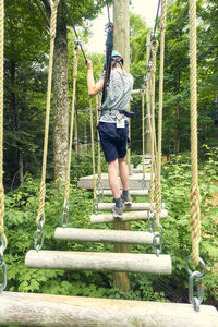 Rear view of boy standing on rope bridge