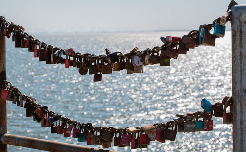 Close-up of love locks hanging on chain against sea