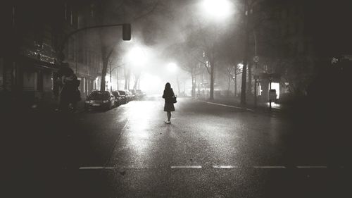 Low angle view of woman standing on illuminated street at night